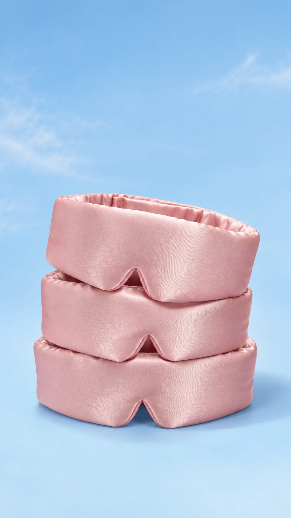 Styled image of three stacked pink silk sleep masks