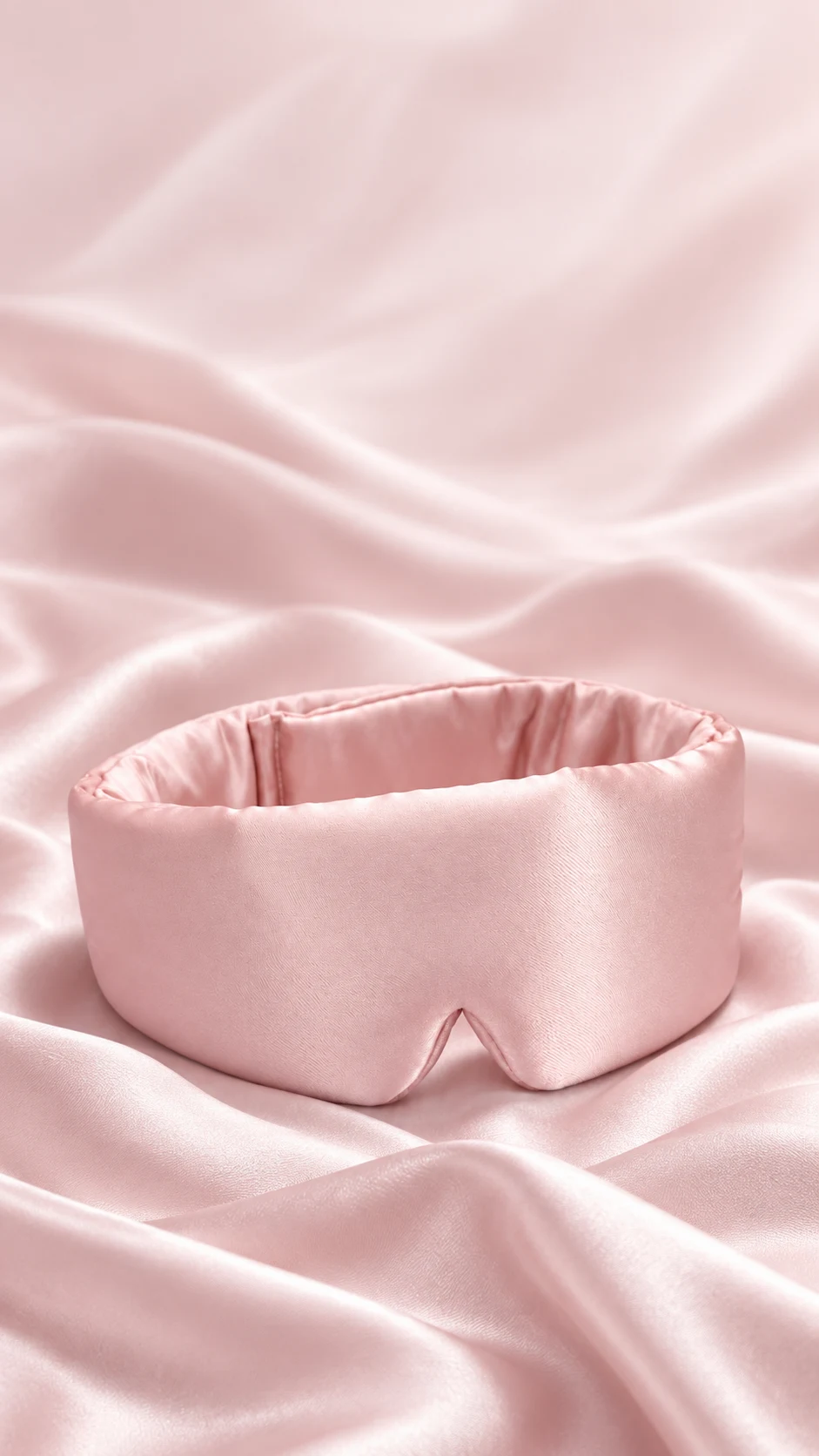 Pink sleep mask against a soft pink fabric backdrop